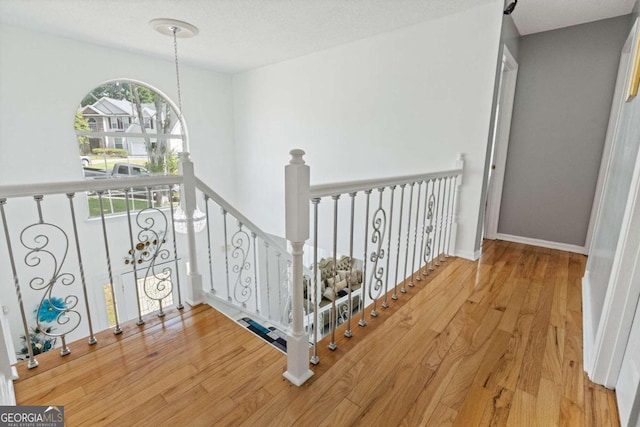 stairs featuring a textured ceiling, wood-type flooring, and a chandelier