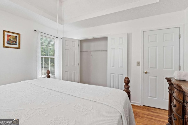 bedroom with a textured ceiling, a closet, and light wood-type flooring