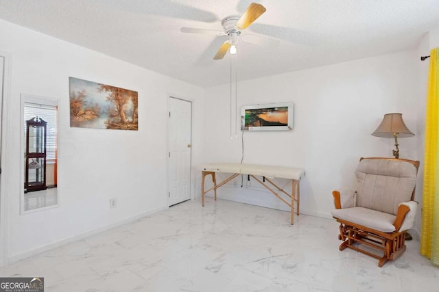 living area featuring ceiling fan and a textured ceiling