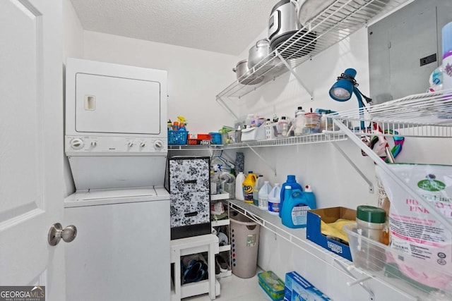 laundry area with a textured ceiling and stacked washer / dryer