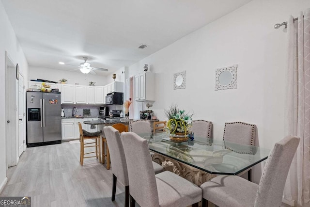 dining area featuring light wood-type flooring, sink, and ceiling fan