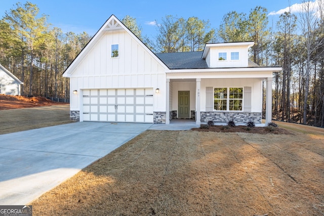 modern farmhouse style home featuring a porch, a front yard, and a garage