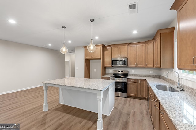 707 Jasmine Dr, Macon, GA 31211 - kitchen featuring stainless steel appliances, a sink, light wood-type flooring, light stone counters, and brown cabinets