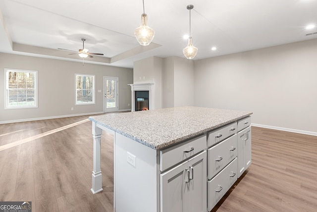 707 Jasmine Dr, Macon, GA 31211 - kitchen featuring a raised ceiling, light wood-style floors, baseboards, a center island, and ceiling fan