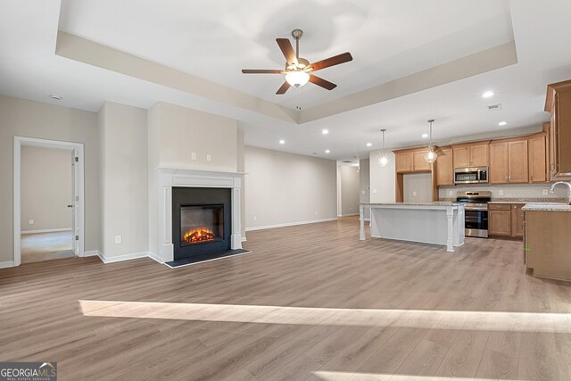 707 Jasmine Dr, Macon, GA 31211 - unfurnished living room featuring a sink, ceiling fan, a raised ceiling, light wood-style floors, and recessed lighting
