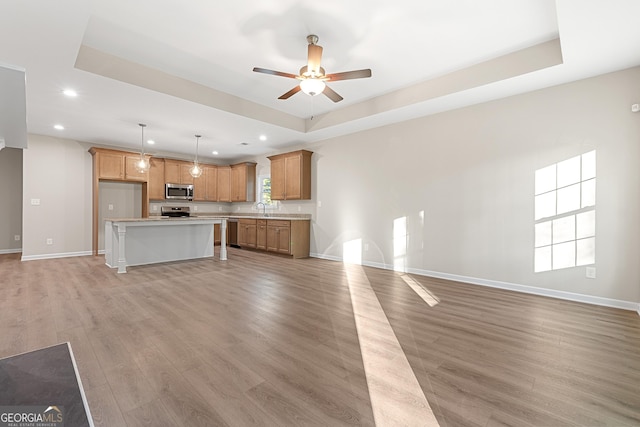 707 Jasmine Dr, Macon, GA 31211 - unfurnished living room featuring a tray ceiling, recessed lighting, light wood-style flooring, a sink, and a ceiling fan