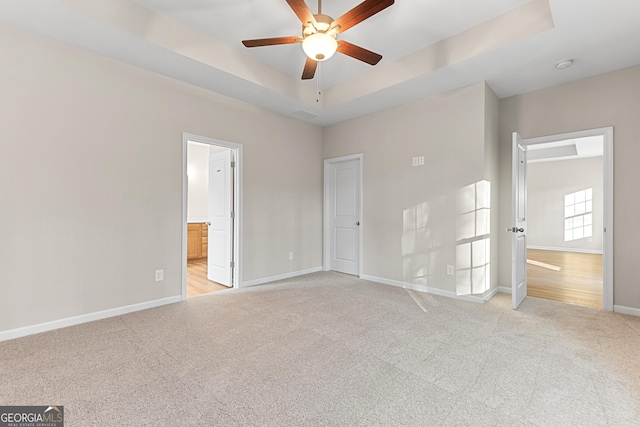 707 Jasmine Dr, Macon, GA 31211 - unfurnished bedroom featuring light carpet, baseboards, a raised ceiling, ensuite bath, and a ceiling fan