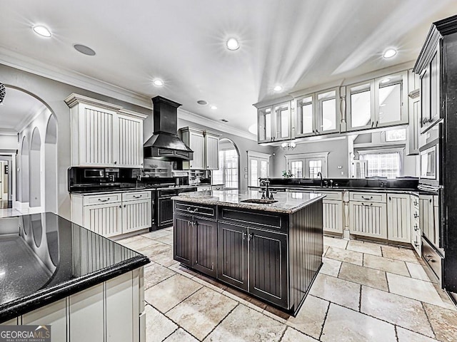 kitchen featuring ornamental molding, premium range hood, recessed lighting, a sink, and backsplash