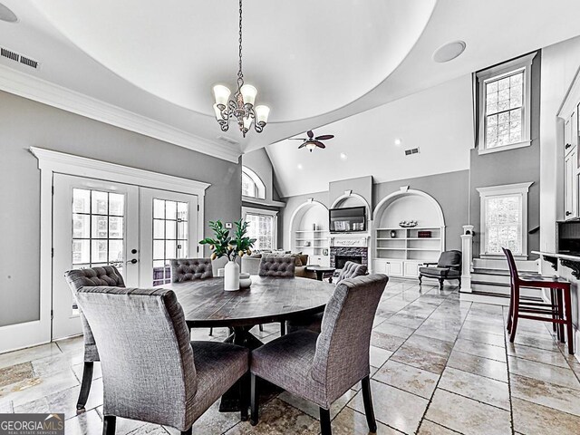 dining space with a ceiling fan, built in features, a chandelier, french doors, and a fireplace