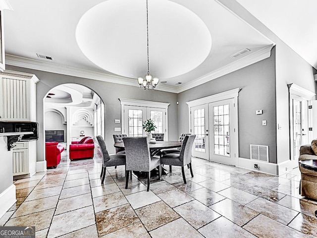 dining room featuring french doors, a chandelier, arched walkways, baseboards, and crown molding
