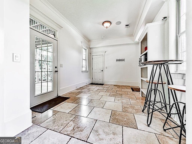 foyer entrance featuring ornamental molding, baseboards, and stone tile floors