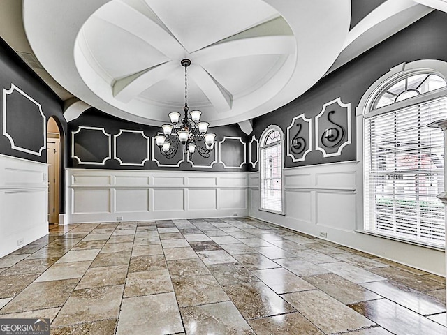 entrance foyer featuring a decorative wall, coffered ceiling, a chandelier, arched walkways, and beamed ceiling