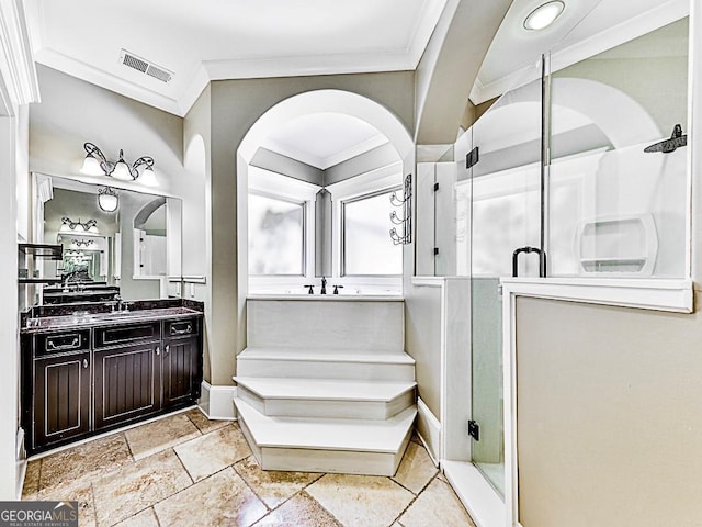 bathroom featuring crown molding, a stall shower, vanity, stone tile floors, and baseboards