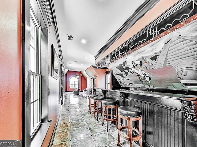 indoor dry bar featuring stone tile floors, recessed lighting, and crown molding
