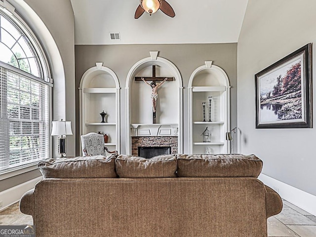 living area with built in shelves, a fireplace, plenty of natural light, ceiling fan, and lofted ceiling