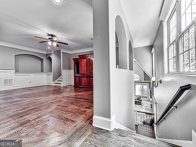 foyer featuring arched walkways, ceiling fan, plenty of natural light, and crown molding