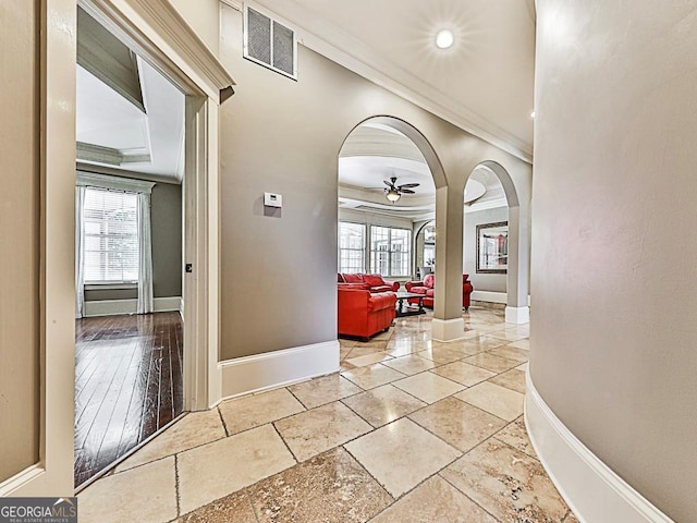corridor with crown molding, arched walkways, baseboards, plenty of natural light, and recessed lighting