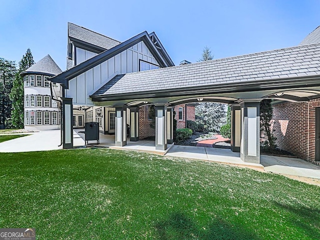 rear view of house with board and batten siding, a lawn, and brick siding