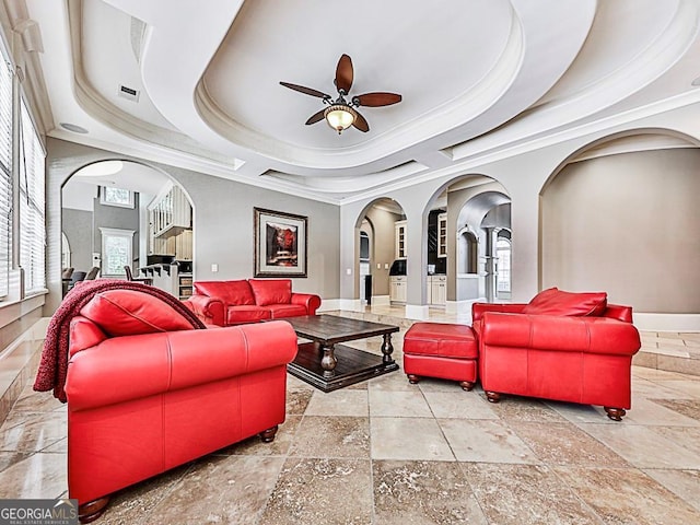 living room featuring a tray ceiling, crown molding, and ceiling fan