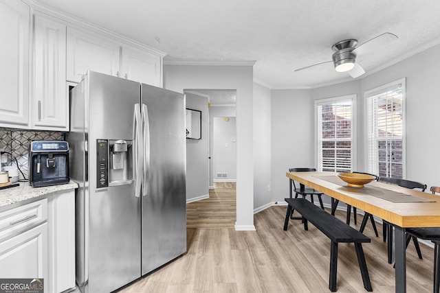 kitchen featuring white cabinets, light hardwood / wood-style flooring, light stone countertops, stainless steel fridge, and ceiling fan