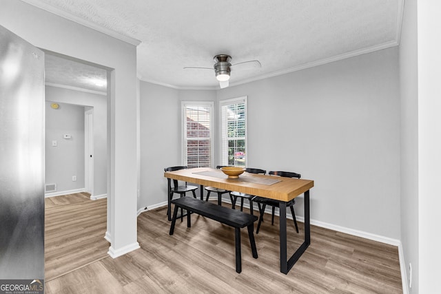 dining area with light wood-type flooring, ceiling fan, crown molding, and a textured ceiling