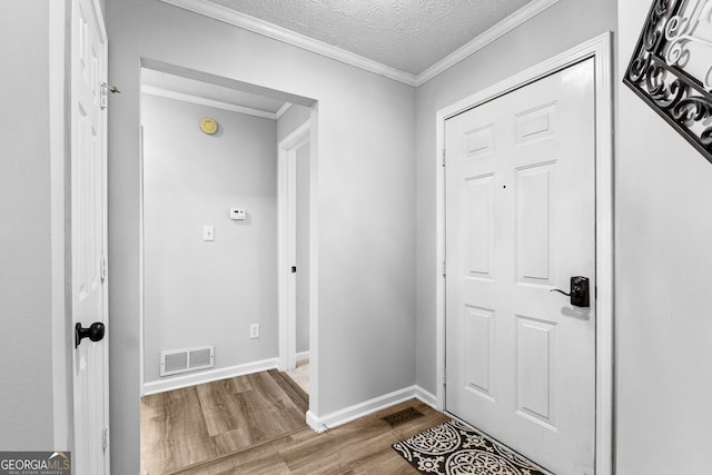 entryway featuring hardwood / wood-style floors, a textured ceiling, and ornamental molding