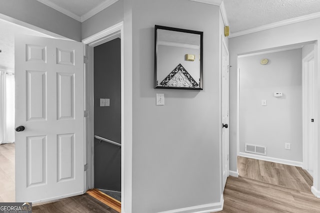 hallway with wood-type flooring, crown molding, and a textured ceiling