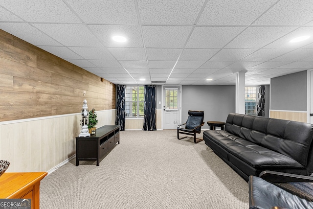 living room with carpet, wooden walls, and a drop ceiling