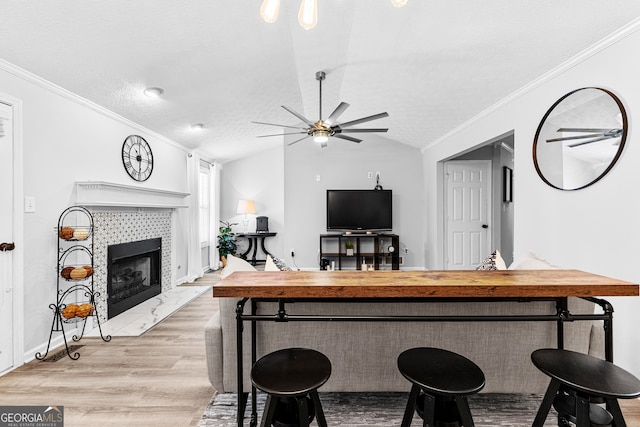 bar with a fireplace, a textured ceiling, ceiling fan, lofted ceiling, and light hardwood / wood-style floors