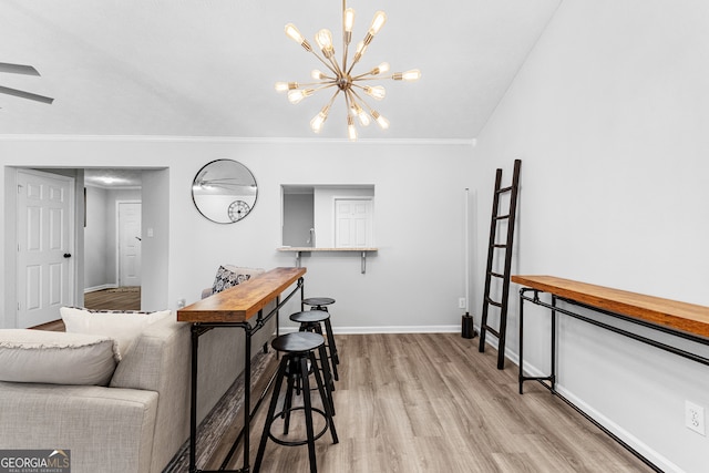 living room featuring crown molding, a notable chandelier, and light hardwood / wood-style flooring