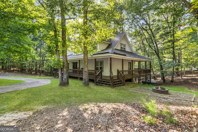 exterior space with a deck, a fire pit, and a front yard