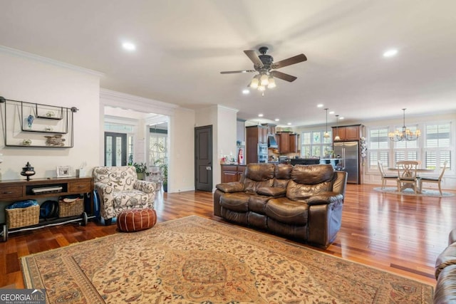 living room with ceiling fan with notable chandelier, crown molding, and wood-type flooring