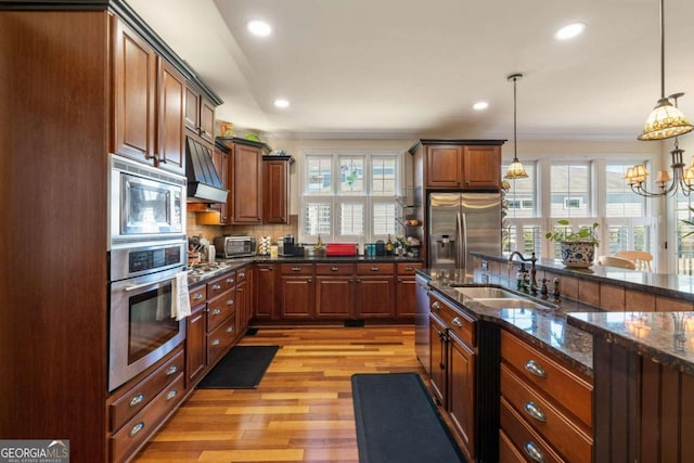 kitchen featuring decorative light fixtures, light hardwood / wood-style flooring, stainless steel appliances, sink, and custom exhaust hood