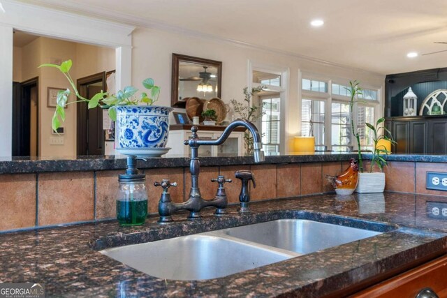 kitchen featuring dark stone countertops, ornamental molding, sink, and ceiling fan