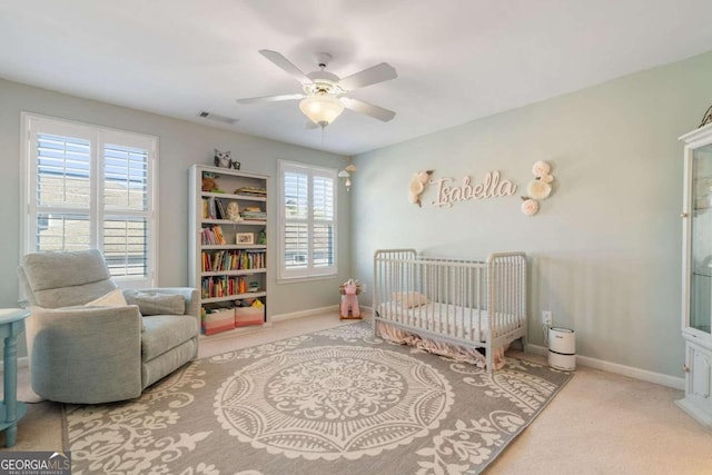 bedroom with ceiling fan, light carpet, and a crib