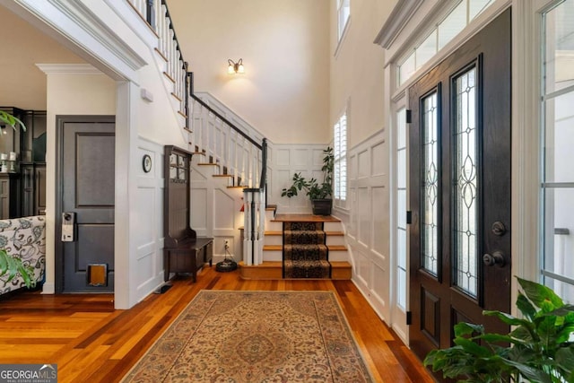 foyer featuring ornamental molding, hardwood / wood-style flooring, and a high ceiling