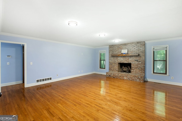 unfurnished living room with ornamental molding, a fireplace, a healthy amount of sunlight, and wood-type flooring