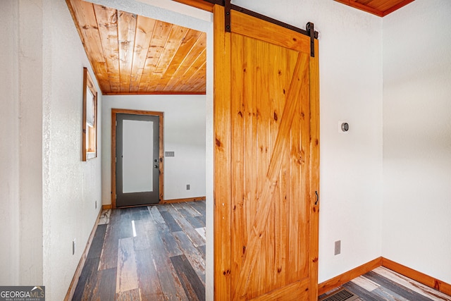 hall with a barn door, dark hardwood / wood-style flooring, wooden ceiling, and vaulted ceiling