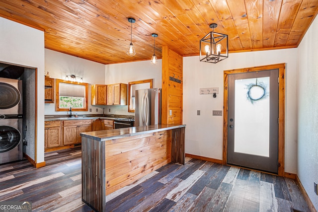 kitchen with decorative light fixtures, stacked washer and clothes dryer, dark hardwood / wood-style flooring, vaulted ceiling, and appliances with stainless steel finishes