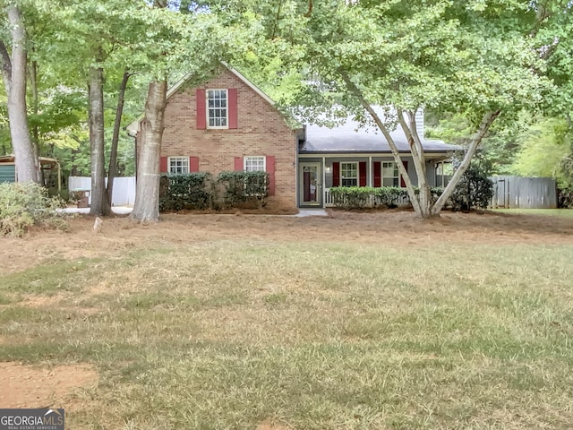 view of front of property with brick siding, a front yard, and fence