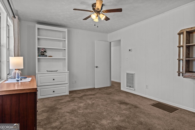 unfurnished bedroom with ceiling fan, a textured ceiling, heating unit, and dark colored carpet