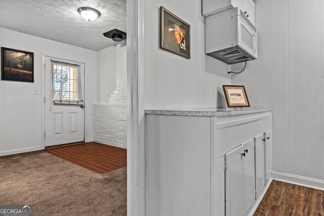 doorway featuring dark carpet and a textured ceiling