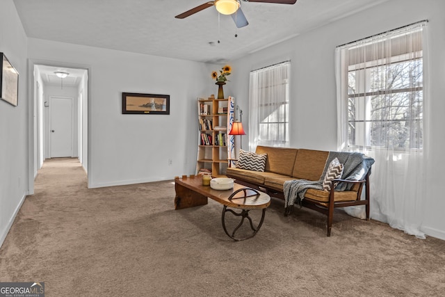 living area featuring a textured ceiling, light colored carpet, and ceiling fan