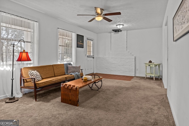 living room featuring ceiling fan, carpet flooring, and a textured ceiling