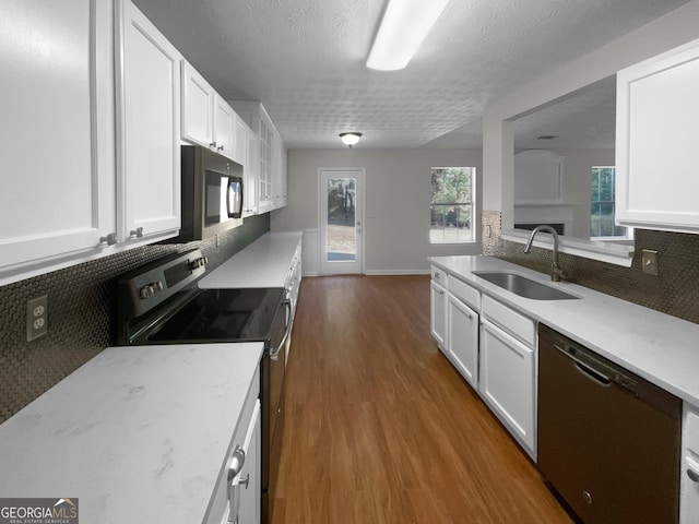 kitchen with dark wood-type flooring, a sink, white cabinetry, appliances with stainless steel finishes, and tasteful backsplash