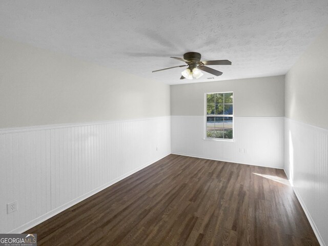 spare room featuring dark wood-type flooring, ceiling fan, and a textured ceiling