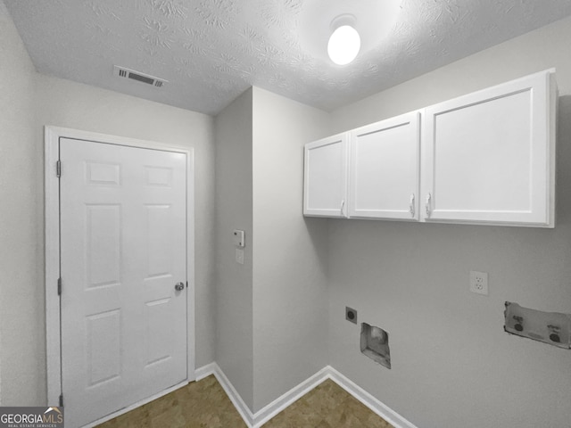 washroom with a textured ceiling, cabinets, hookup for a washing machine, and hookup for an electric dryer