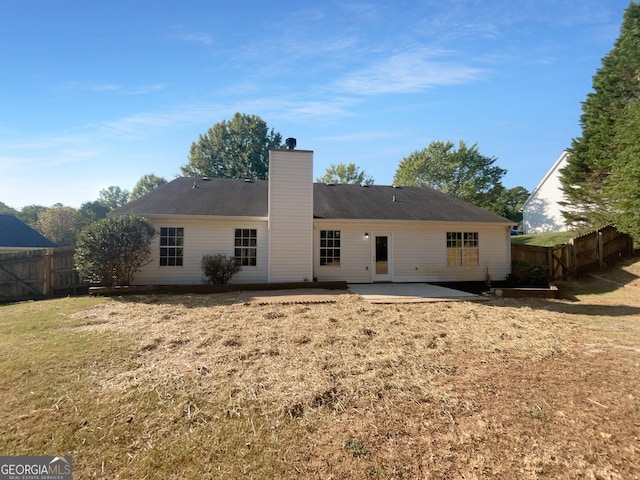 rear view of property featuring fence private yard, a lawn, a chimney, and a patio