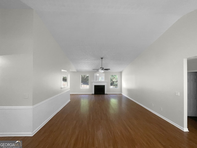 unfurnished living room with vaulted ceiling, dark hardwood / wood-style floors, and ceiling fan