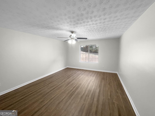 empty room featuring a textured ceiling, ceiling fan, dark wood finished floors, and baseboards